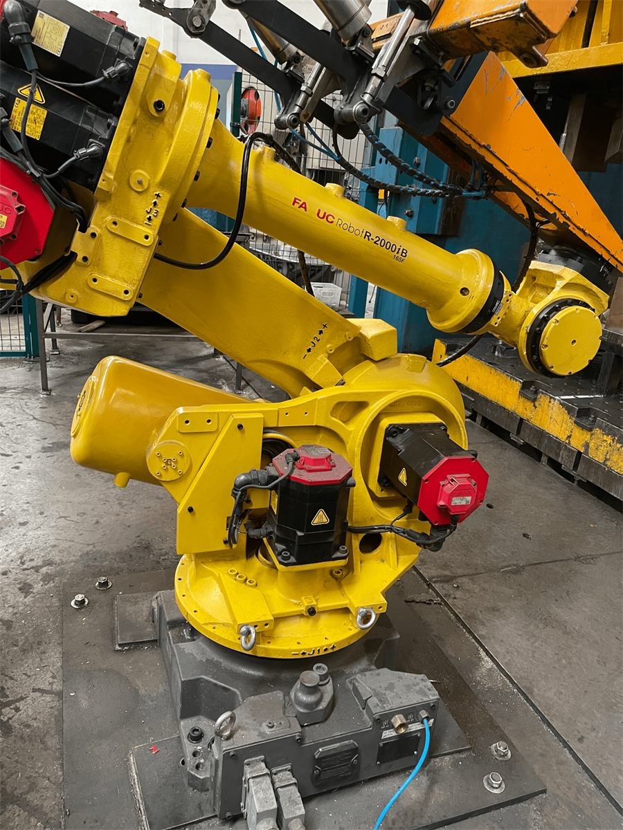 Robot FANUC R-2000 amarillo en la celda de estampado